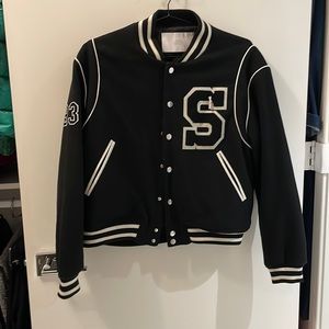 Black STAMPD varsity jacket with varsity letters on front